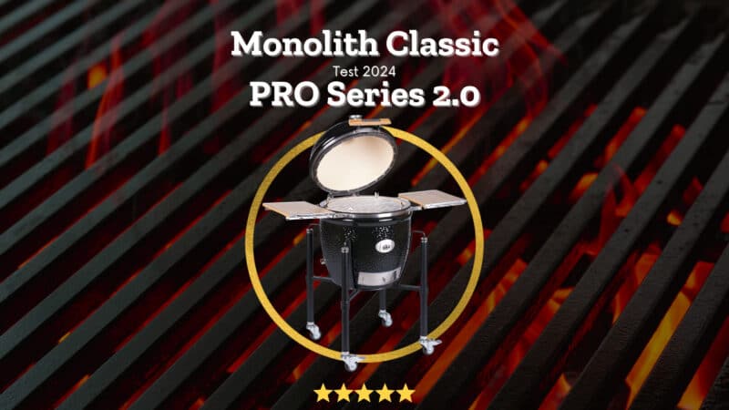 Monolith Classic PRO Series 2.0 Keramikgrill mit geöffnetem Deckel auf einem Gestell, umgeben von einem goldenen Kreis mit fünf Sternen Bewertung, vor glühenden Holzkohlen.