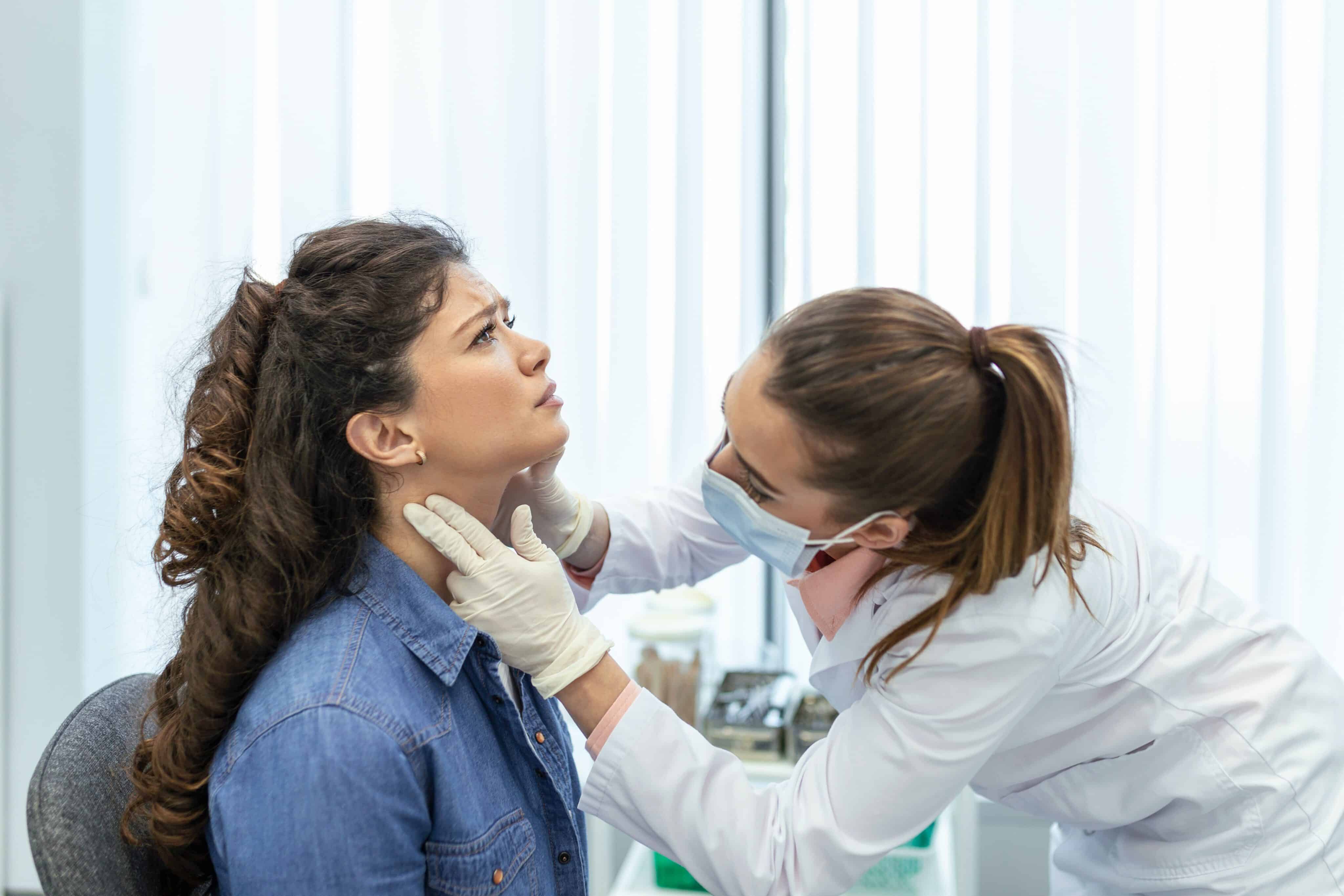 Ein Arzt untersucht eine Patientin auf Schilddrüsenerkrankungen, um mögliche Störungen in der Schilddrüsenfunktion zu identifizieren. Diese Erkrankungen können zu Symptomen wie Müdigkeit und Erschöpfung führen, die durch eine genaue Untersuchung und Behandlung gelindert werden können.