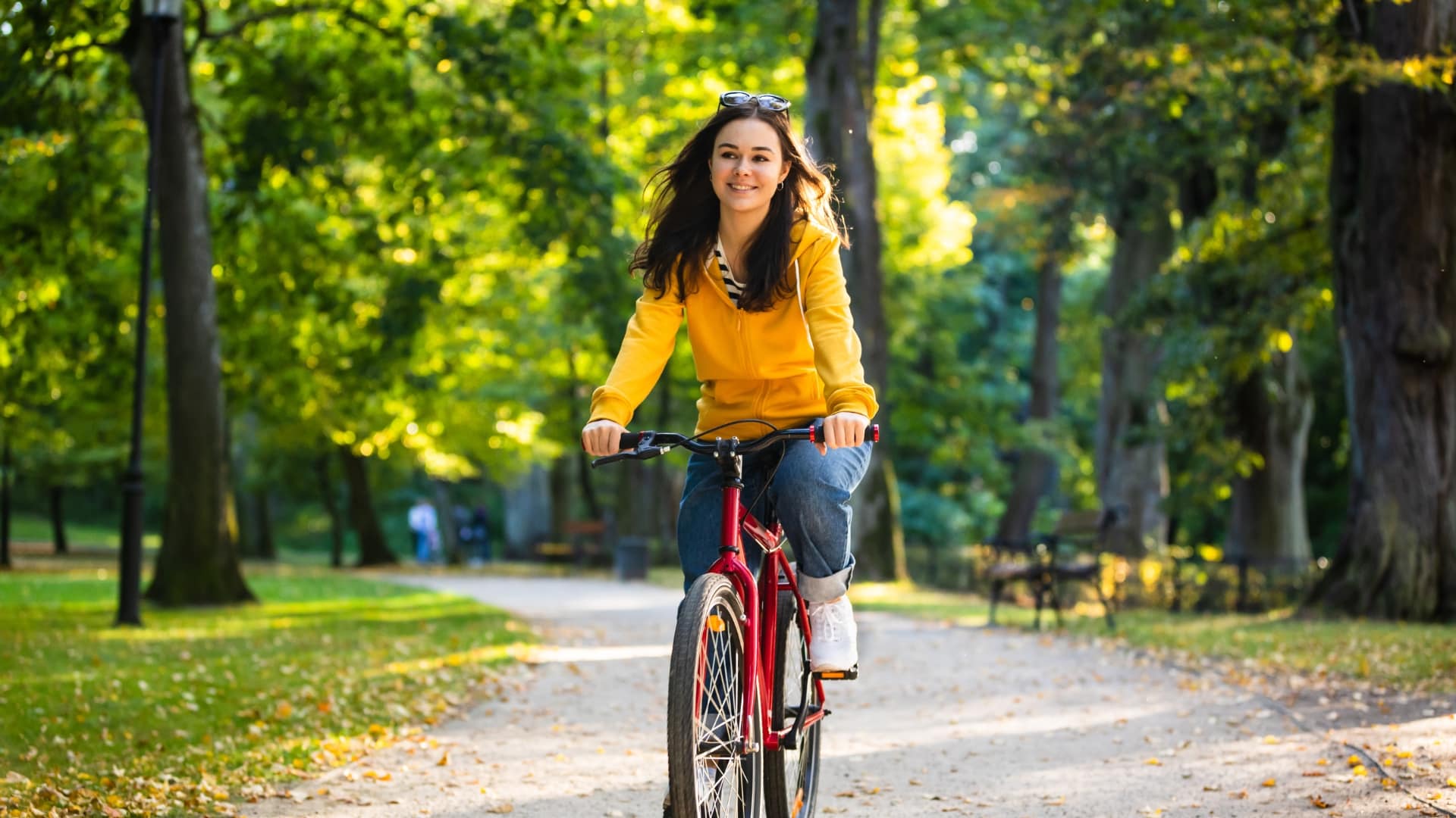 Fröhliche Person beim Radfahren im Park, illustriert die Bedeutung von Sport für die Bewältigung von Akne Inversa.