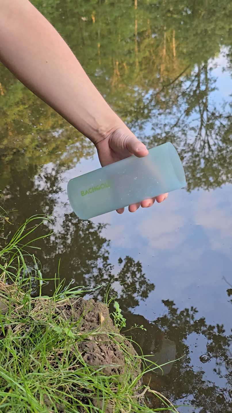 Person entnimmt Wasser aus einem stehenden ruhigen See mit dem Äußeren Gefäß