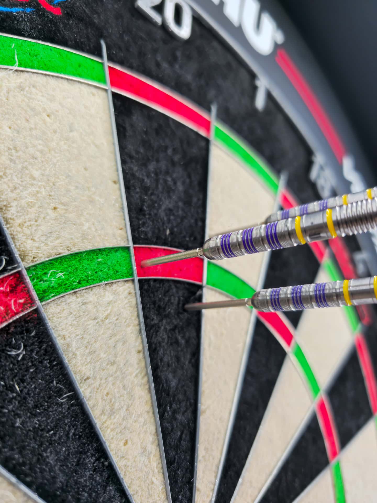 Drei Darts mit 35 mm Swiss Point Spitzen stecken eng nebeneinander im Triple 20 – Seitenansicht