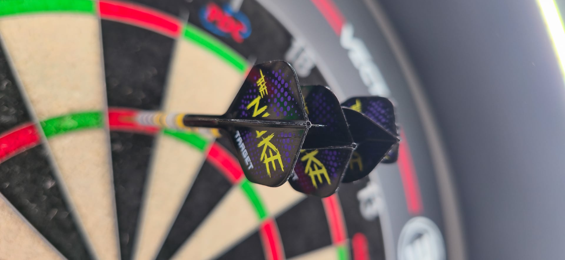 Drei stark beanspruchte Target K-Flex Darts im Board nach drei Monaten intensiver Nutzung – sichtbare Abnutzung durch Gruppierung