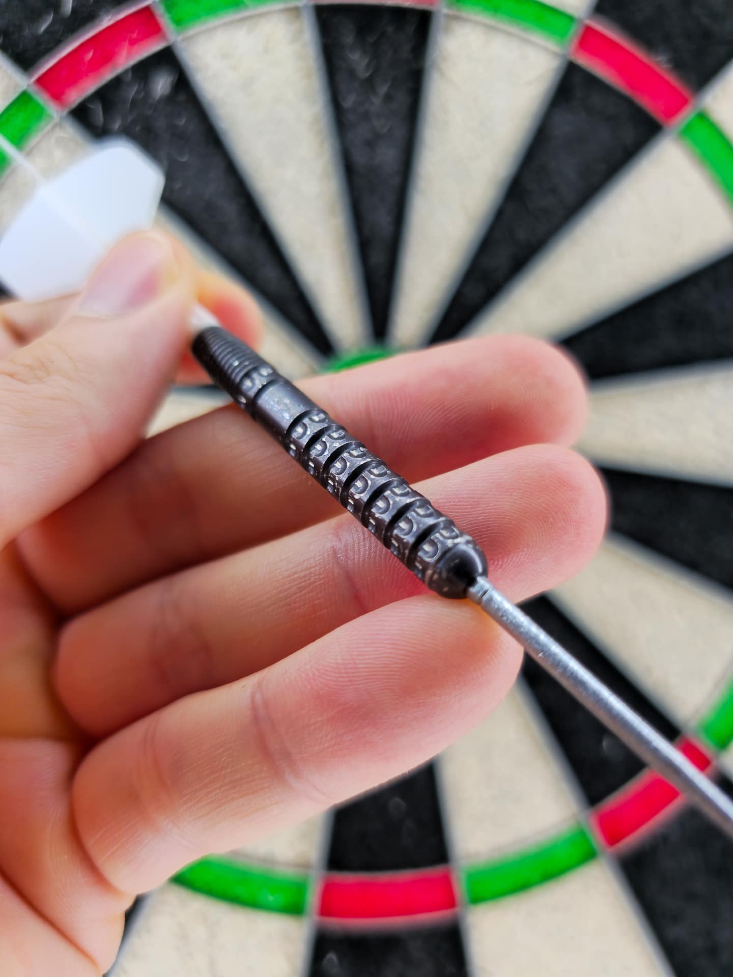 Luke Littler G1 SP Dart-Barrel mit weißem K-Flex Short-Shaft vor der Dartscheibe, Seitenansicht