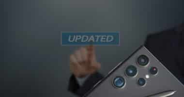 Hand tippt auf einen schwebenden „UPDATED“-Schriftzug; daneben die Rückseite eines Samsung-Smartphones mit Mehrfachkamera und S Pen – Symbolbild für ein Software-Update.