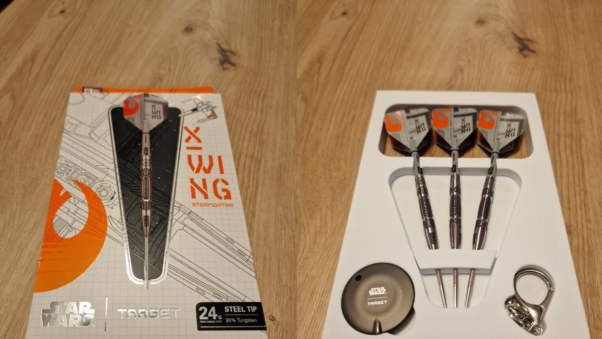 Target Star Wars X-Wing Steeldarts mit Originalverpackung, drei montierten Darts, Swiss Point Tool und Star-Wars-Schlüsselanhänger auf Holztisch.