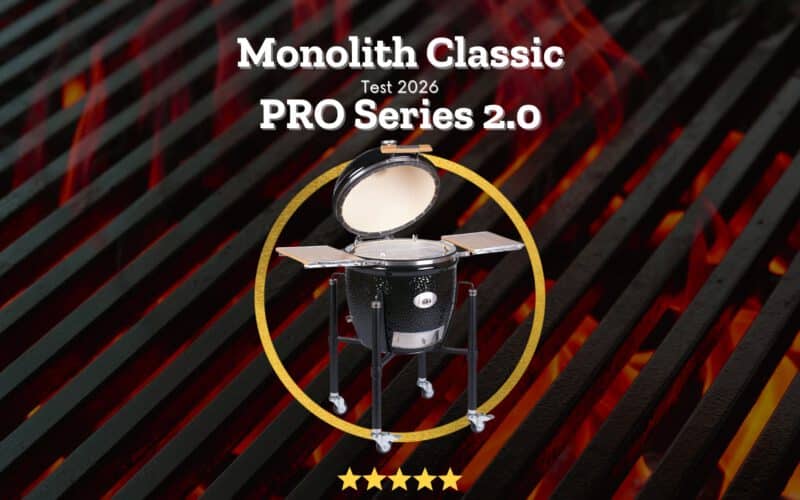 Monolith Classic PRO Series 2.0 Keramikgrill mit geöffnetem Deckel auf einem Gestell, umgeben von einem goldenen Kreis mit fünf Sternen Bewertung, vor glühenden Holzkohlen.